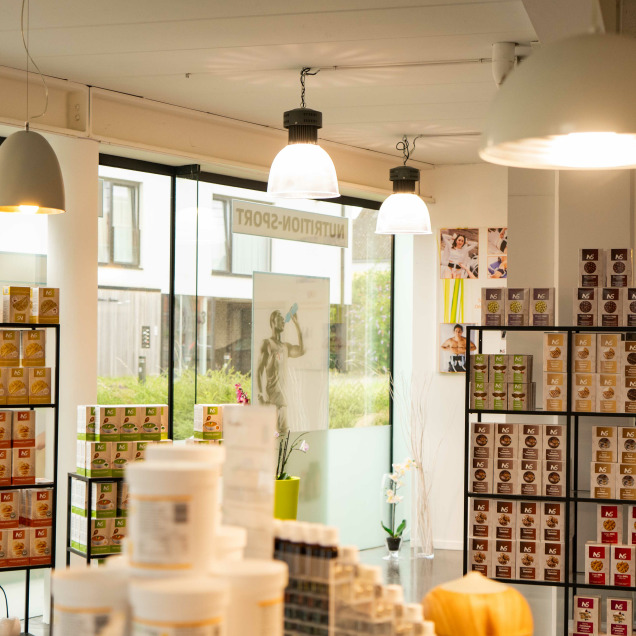 Intérieur du magasin Nutrishop à Rocourt avec des étagères remplies de compléments alimentaires et une décoration moderne.