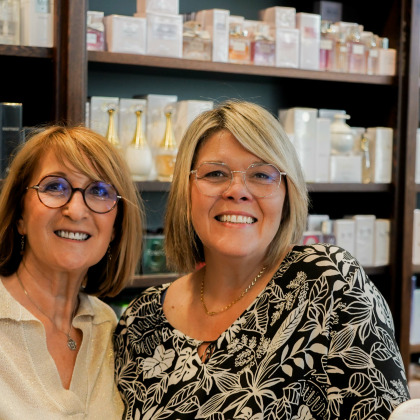 Les gérantes de la parfumerie Tiffani à Herve, souriantes devant des étagères de parfums.