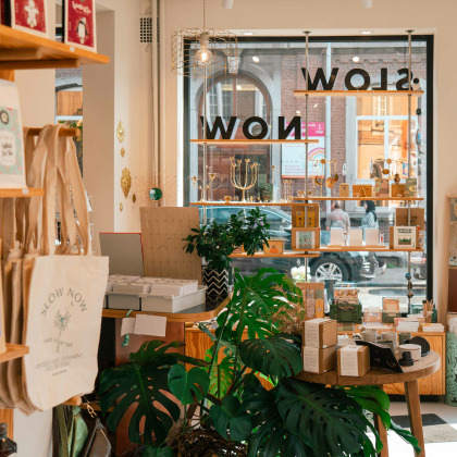 Intérieur de l'épicerie Slow Now à Liège, présentant des produits durables, des accessoires et des articles écoresponsables dans un cadre chaleureux et lumineux.