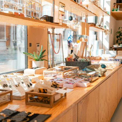 Intérieur de l'épicerie Slow Now à Liège, avec des présentoirs de bijoux, accessoires et autres articles écoresponsables en vitrine.