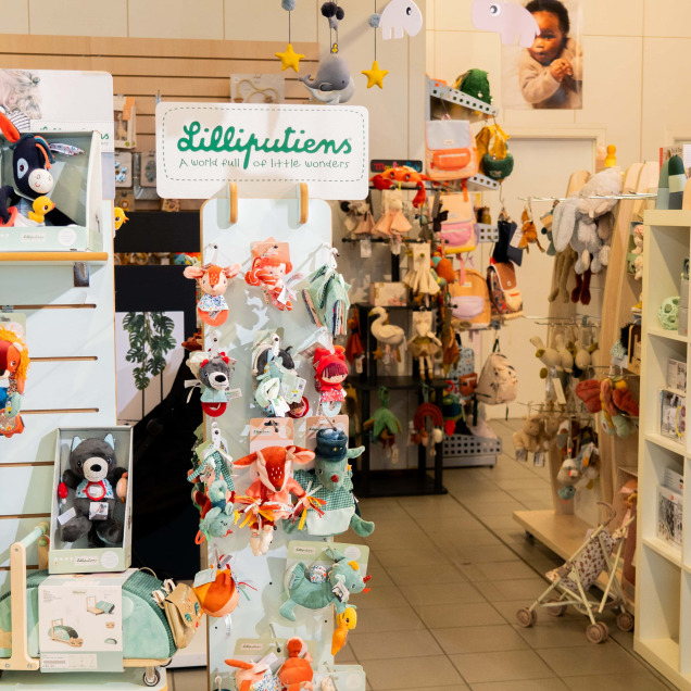 Intérieur du magasin pour bébés Ptilou à Rocourt, spécialisé dans les produits pour bébés, avec des jouets, peluches et accessoires exposés.