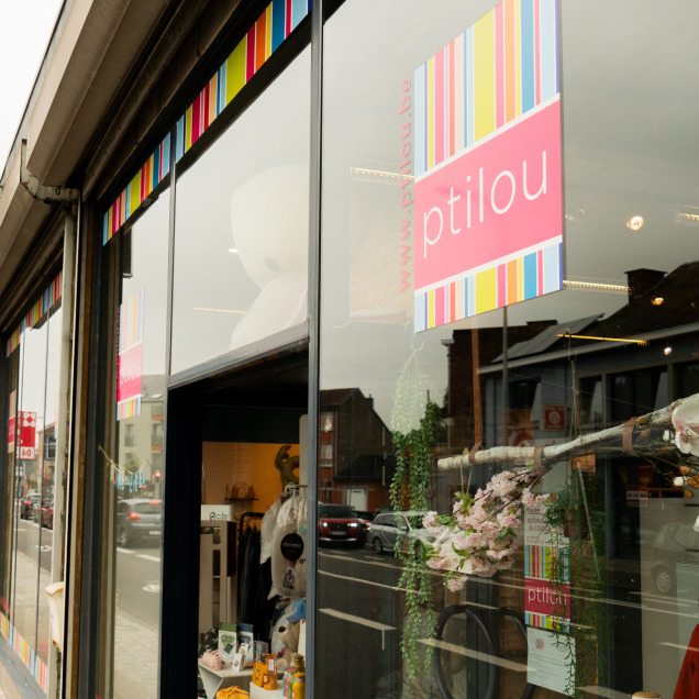 Vue extérieure du magasin pour bébés Ptilou à Rocourt, avec sa vitrine colorée et le logo visible.