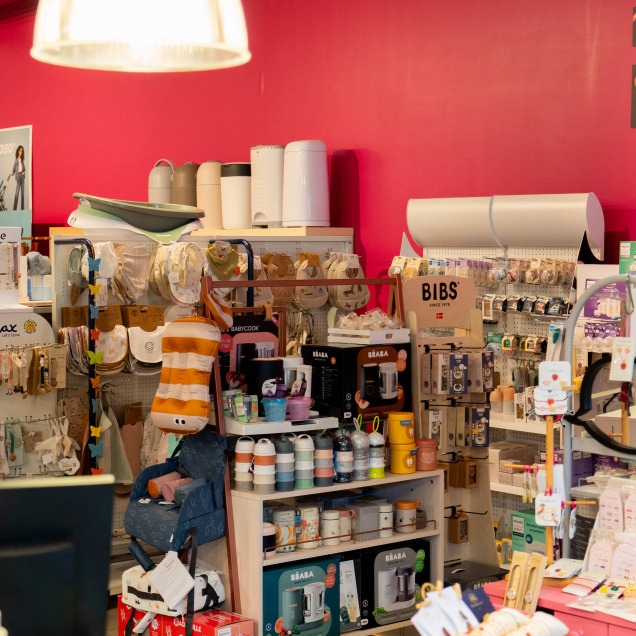 Rayon de produits pour bébés chez Ptilou à Rocourt, avec des accessoires de puériculture et des jouets exposés sur des étagères colorées.