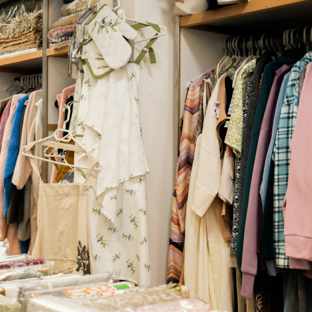 Intérieur du magasin Matin Coton à Visé, spécialisé en linge de maison et fin de séries, avec des rayons de textiles colorés et vêtements suspendus.