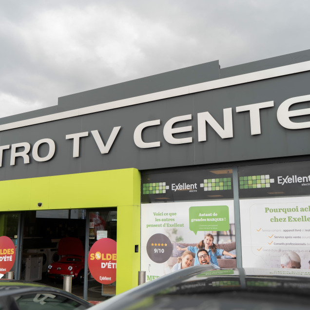 Devanture du magasin Electro TV Center à Boncelles, avec le logo Exellent et des affiches de promotions en vitrine.