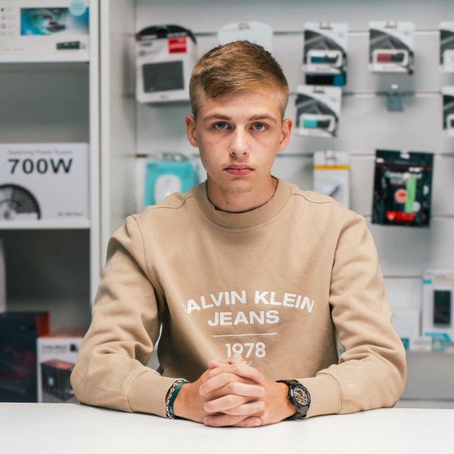 Jeune homme assis devant un ordinateur dans le magasin d'informatique Pecebel à Liège.