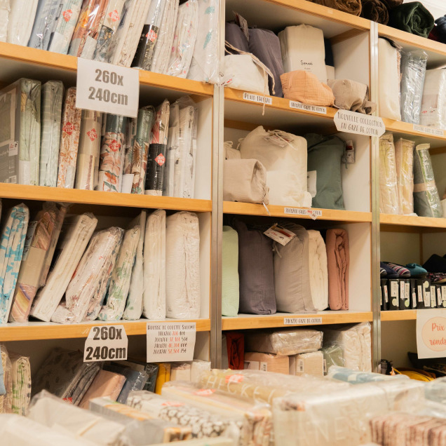 Intérieur du magasin Matin Coton à Visé, spécialisé en linge de maison et fin de séries, avec du linge de lit bien trié