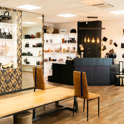 Intérieur du magasin “Chaussures Lehane” à Visé, avec des chaussures et des sacs à main exposés sur des étagères.