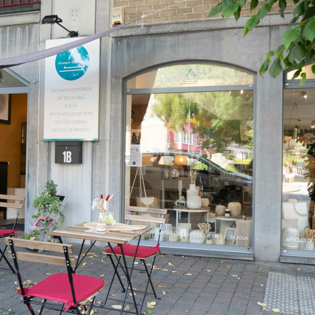 Devanture du magasin “Humeur du jour” à Visé. Devant le magasin, il y a de petites tables avec des chaises rouges pour les clients. La devanture a de grandes fenêtres qui permettent de voir les articles exposés à l’intérieur.