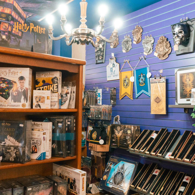 Intérieur du magasin “Le Reliquaire” à Liège. Les murs sont peints en bleu et décorés avec des objets comme des cadres et des bannières de maisons de la série Harry Potter.