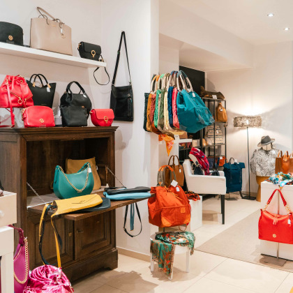 Intérieur de la boutique “Mon sac à moi” à Liège, avec une variété de sacs colorés exposés sur des étagères, des tables et des présentoirs.