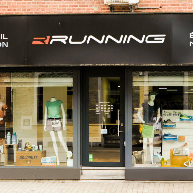 Devanture du magasin “Rrunning Tilff” à Esneux. La façade noire affiche le nom du magasin en grandes lettres blanches. Les vitrines exposent des chaussures et des vêtements de sport.