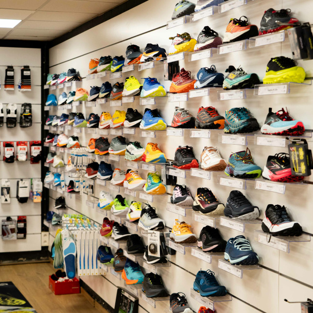 De nombreuses chaussures de sport exposées sur des étagères murales au magasin “Rrunning Tilff” à Esneux