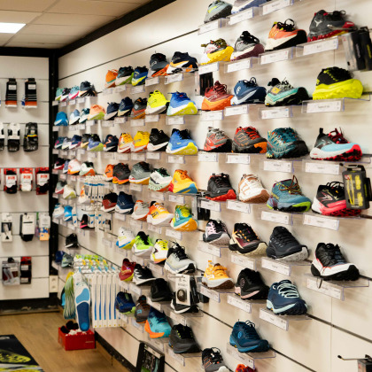 De nombreuses chaussures de sport exposées sur des étagères murales au magasin “Rrunning Tilff” à Esneux