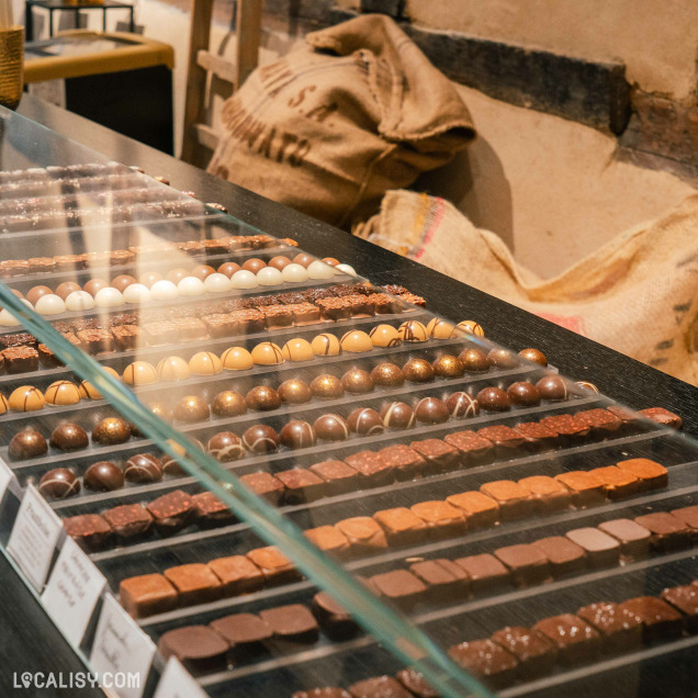 Variété de chocolats exposés dans une vitrine en verre au magasin “Carré Noir” à Liège, mettant en avant des confiseries gourmet.