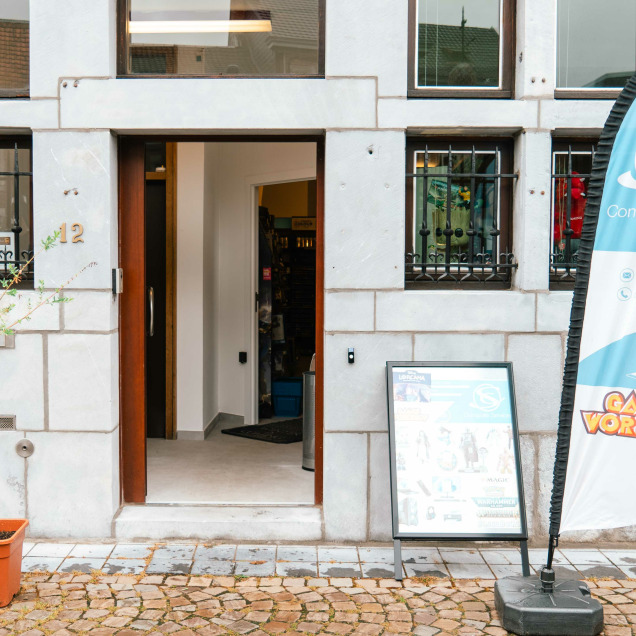 Devanture du magasin “Computer Services” à Theux avec une bannière bleue-blanche et le logo du magasin. Un panneau sur le trottoir présente les services et la porte est ouverte, invitant les clients à entrer.