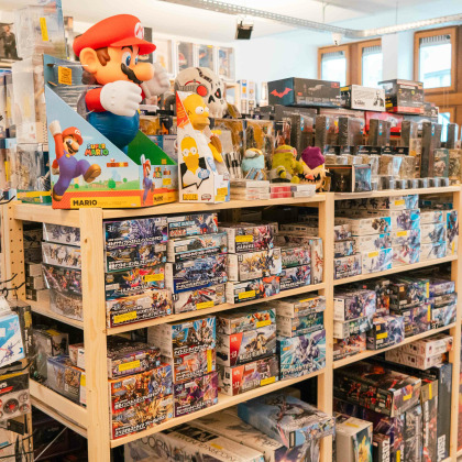 L’intérieur du magasin “Computer Services” à Theux présente des étagères remplies de jeux vidéo et d’accessoires. Une grande figurine de Mario ajoute une touche ludique à l’environnement axé sur la technologie.