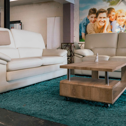 deux canapés en cuir beige placés autour d'une table basse en bois, sur un tapis bleu  dans le showroom Quality confort à Saint Georges-sur-Meuse.