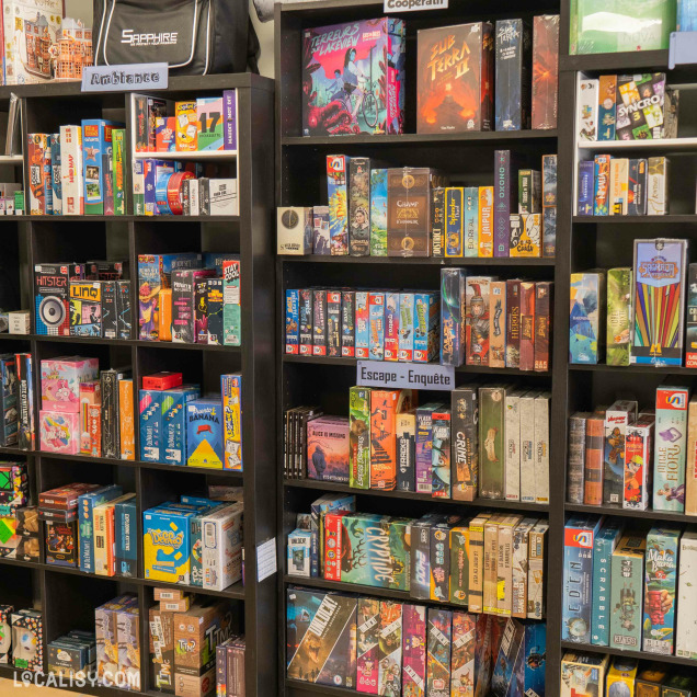 L’intérieur du magasin “En Jeux-Tu ? En Voilà !” à Saint-Georges-sur-Meuse montre des étagères bien remplies de jeux de société variés, adaptés à tous les âges et intérêts.