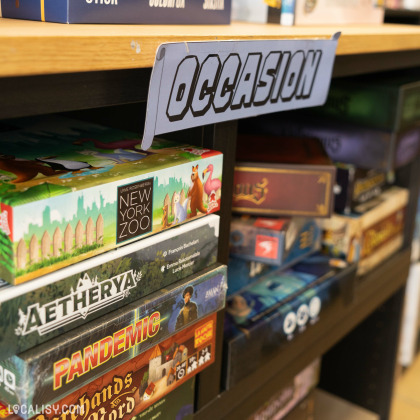 Des jeux de société d’occasion comme “New York Zoo” et “Pandemic” sont exposés sur une étagère dans le magasin “En Jeux-Tu ? En Voilà !” à Saint-Georges-sur-Meuse.