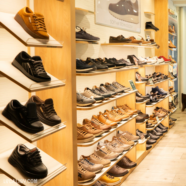 Plusieurs étagères murales avec des chaussures exposées, principalement des modèles pour hommes et femmes dans le magasin “Mephisto Shop” à Liège.