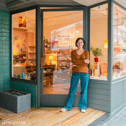 Devanture du magasin “Ma maison bien-aimée” à Liège. La vitrine en verre laisse entrevoir divers articles de décoration intérieure. Une personne se tient devant le magasin.