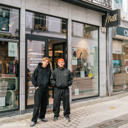 Devanture du magasin “MILK” à Liège. La façade est noire avec le nom du magasin en lettres cursives blanches au-dessus de l’entrée, deux personnes se tiennent devant le magasin.