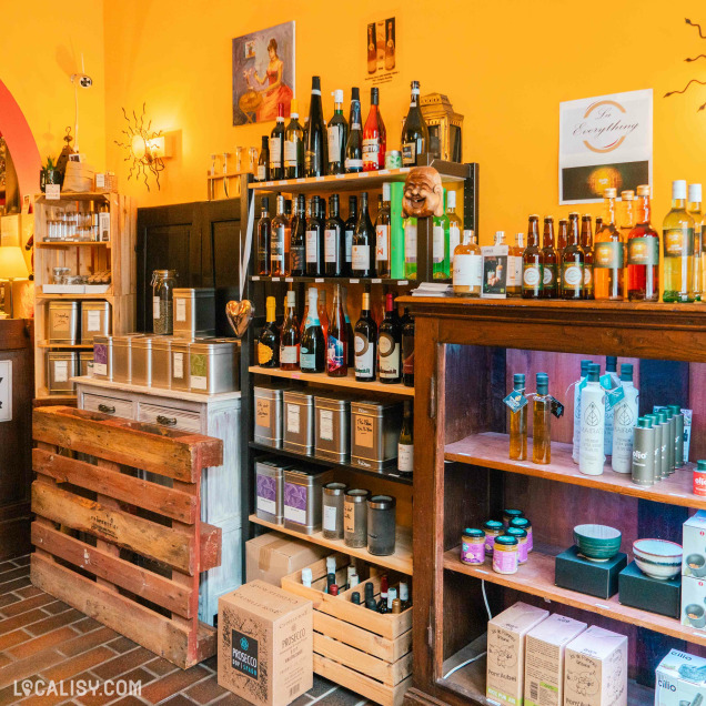 L’intérieur du magasin “Graines d’épices” à Liège, avec des produits variés exposés sur des étagères en bois et des caisses. On y voit des bouteilles, des boîtes, des bocaux contenant des épices et des aliments.