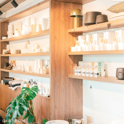 Étagère élégante au Fika Concept Store à Aubel, présentant une sélection de parfums d'ambiance, de diffuseurs, de bougies et de coussins décoratifs.