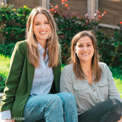 Sur cette photo, deux femmes souriantes posent à l'extérieur, représentant l'équipe de l'e-commerce Sista à Aywaille, dans un cadre verdoyant.