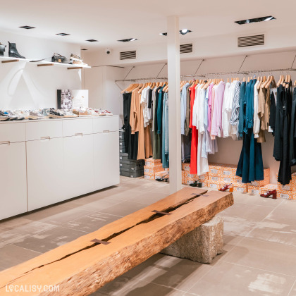 Rayon de vêtements et chaussures au magasin Ygreque à Liège, avec banc en bois pour les essayages