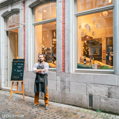 Devanture du magasin “L’Effervescence” à Liège avec une façade vitrée, laissant entrevoir des articles variés et une ambiance chaleureuse. Un panneau en ardoise sur le trottoir affiche des informations.