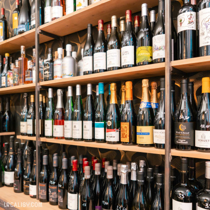 Le magasin “L’Effervescence” à Liège présente des étagères bien organisées avec une grande variété de bouteilles de vin et de champagne.