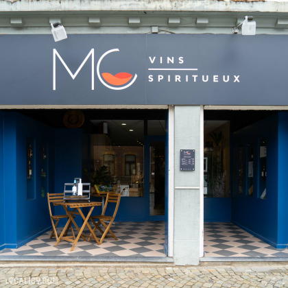 Devanture du magasin “MC Vins” à Theux. La façade est peinte en bleu vif, avec le nom et le logo du magasin bien visibles au-dessus de l’entrée.