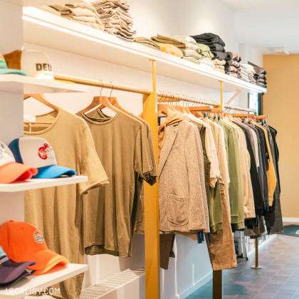 Intérieur du magasin "Monsieur Lascar" à Battice avec des vêtements classes et des accessoires dans une ambiance chaleureuse.