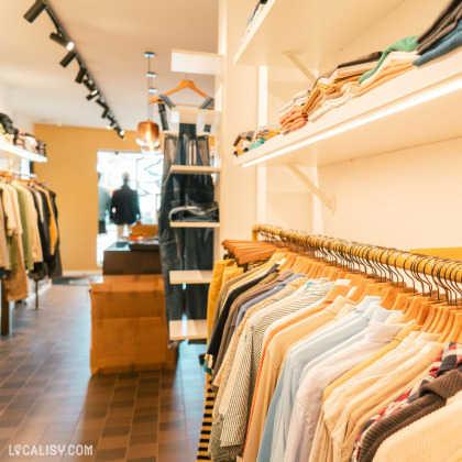 Intérieur du magasin "Monsieur Lascar" à Battice avec une tringle de vêtements hommes