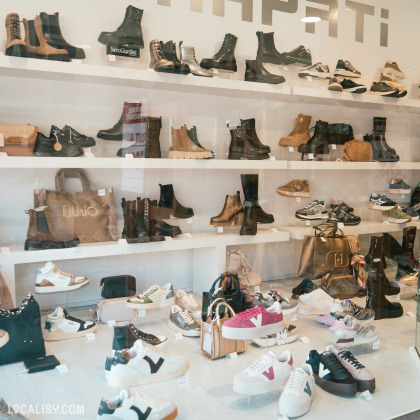 La vitrine du magasin “Chapati/La Good’as” à Aywaille, avec une variété de chaussures et de sacs exposés.