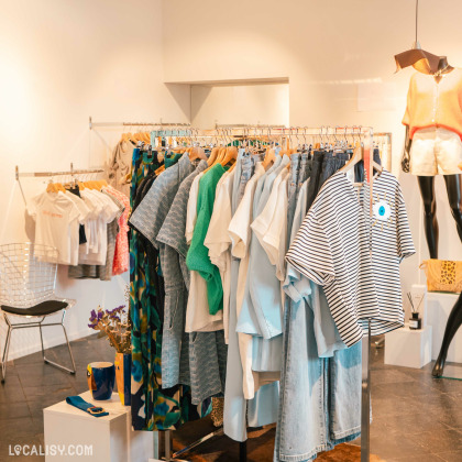 L’intérieur du magasin “BRUNE Concept Store” à Beaufays, avec des vêtements sur des portants et des étagères dans un espace moderne et lumineux.