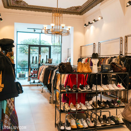 L’intérieur du magasin “Lulu Store” à Liège, avec divers vêtements et accessoires exposés. On y voit des portants avec des vêtements, une étagère avec des chaussures, et des sacs à main sur une table.