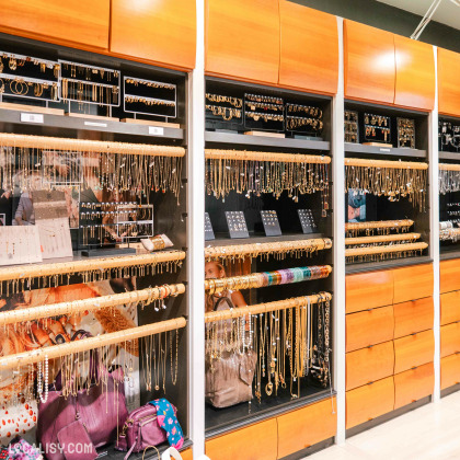 L’intérieur de la boutique “Coco Bijoux et Accessoires” à Liège, avec divers bijoux et accessoires exposés sur des panneaux muraux et des étagères.