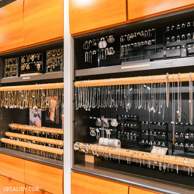 L’intérieur de la boutique “Coco Bijoux et Accessoires” à Liège, avec divers bijoux exposés dans une vitrine bien éclairée.