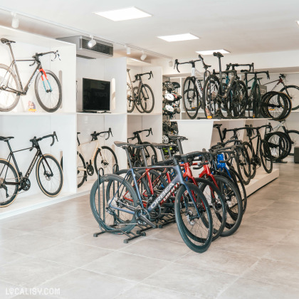 L’intérieur du magasin “Respire Sports Bike” à Spa, avec une variété de vélos exposés sur des supports au sol et des montures murales.