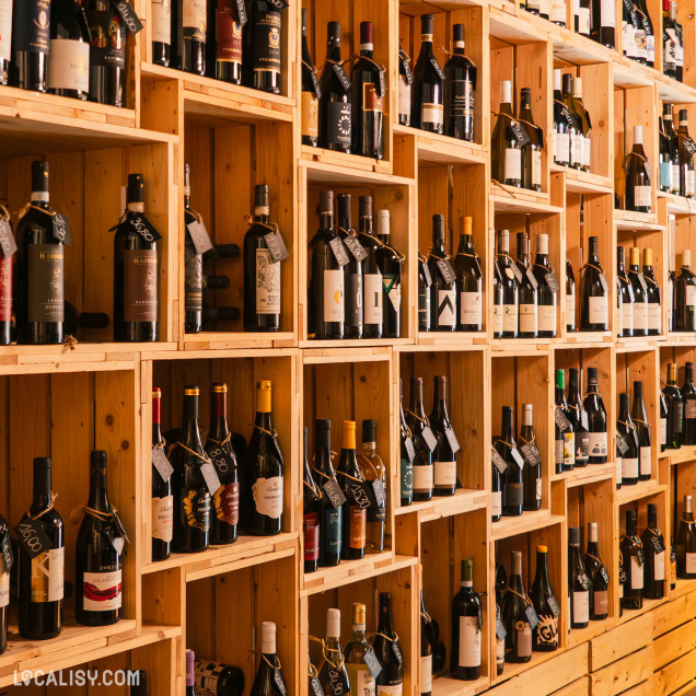 Une étagère en bois remplie de diverses bouteilles de gin, suggérant que le magasin “Les Vignes en Ville” à Liège propose une large sélection de spiritueux, en particulier du gin.