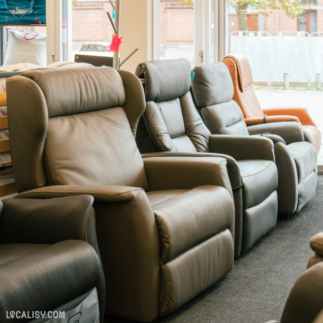 Un présentoir de fauteuils inclinables à l’intérieur du magasin "Rio Meubles" à Liège. Les fauteuils sont disposés en rangée, présentant différentes couleurs et styles.