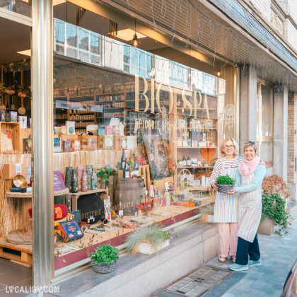 Annick devant la vitrine du magasin d'épicerie "BIO SPA" à Spa.