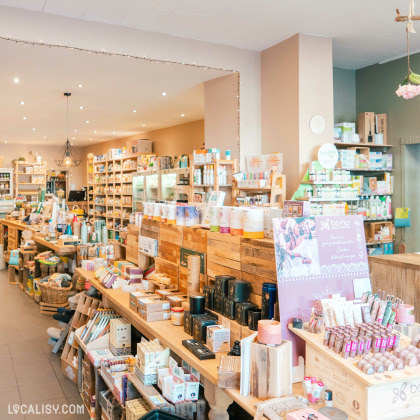 Magasin de produits naturels avec étagères remplies de compléments alimentaires et décor floral suspendu à Spa.