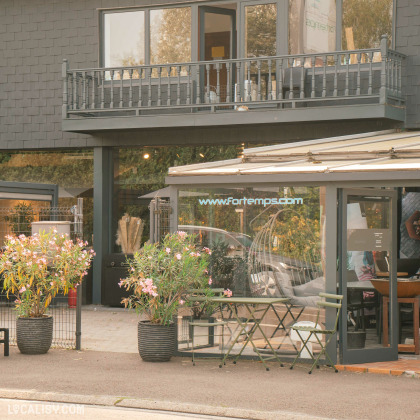 Devanture du magasin de mobilier de jardin Fortemps SRL à Soumagne avec deux grandes vitrines exposant des fleurs et des plantes, et à l’extérieur, un étalage de diverses plantes en pot et fleurs à vendre.