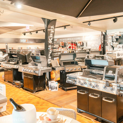 L’intérieur du magasin de mobilier de jardin Fortemps SRL à Soumagne, avec une variété de meubles d’extérieur, y compris des tables avec des assiettes et des couverts, des chaises, et de grands parasols.