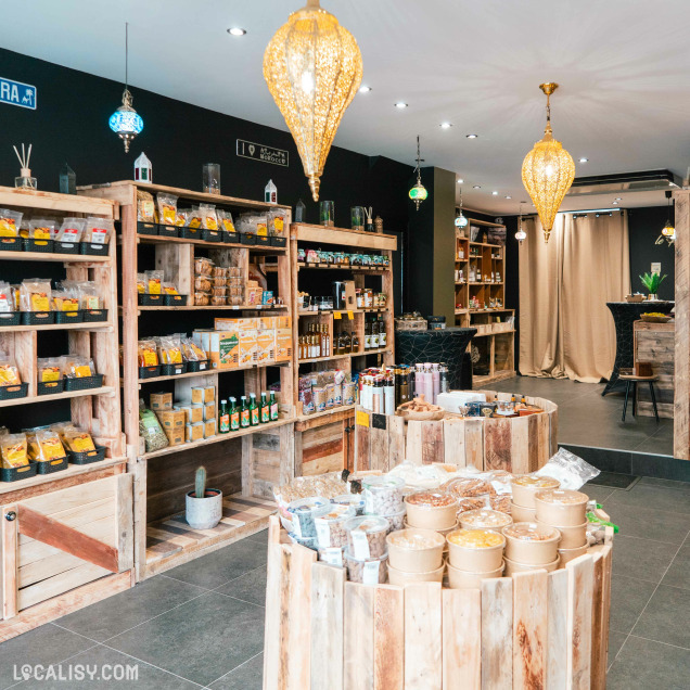 Intérieur de Le Panier du Sud à Verviers avec étagères en bois remplies de produits d'épicerie et des lampes suspendues d'inspiration orientale.