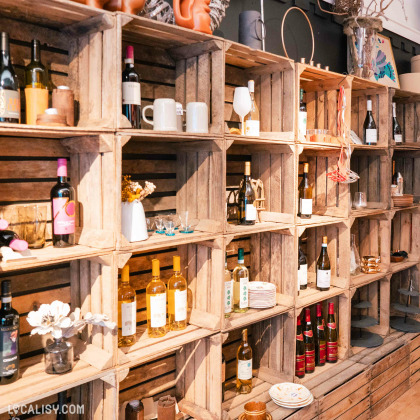 Intérieur de la boutique Le Petit Repère à Liège avec un ensemble  d'étagères , présentant des objets de décoration, des produits chinés, des bougies et des vins.